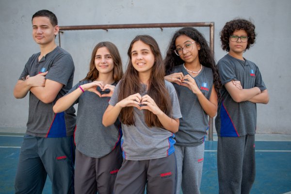 Alunos do Ensino Fundamental 2, um ao lado do outro, fazendo pose.